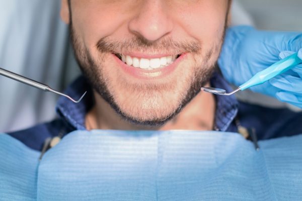 Unrecognizable male patient having teeth whitening procedure